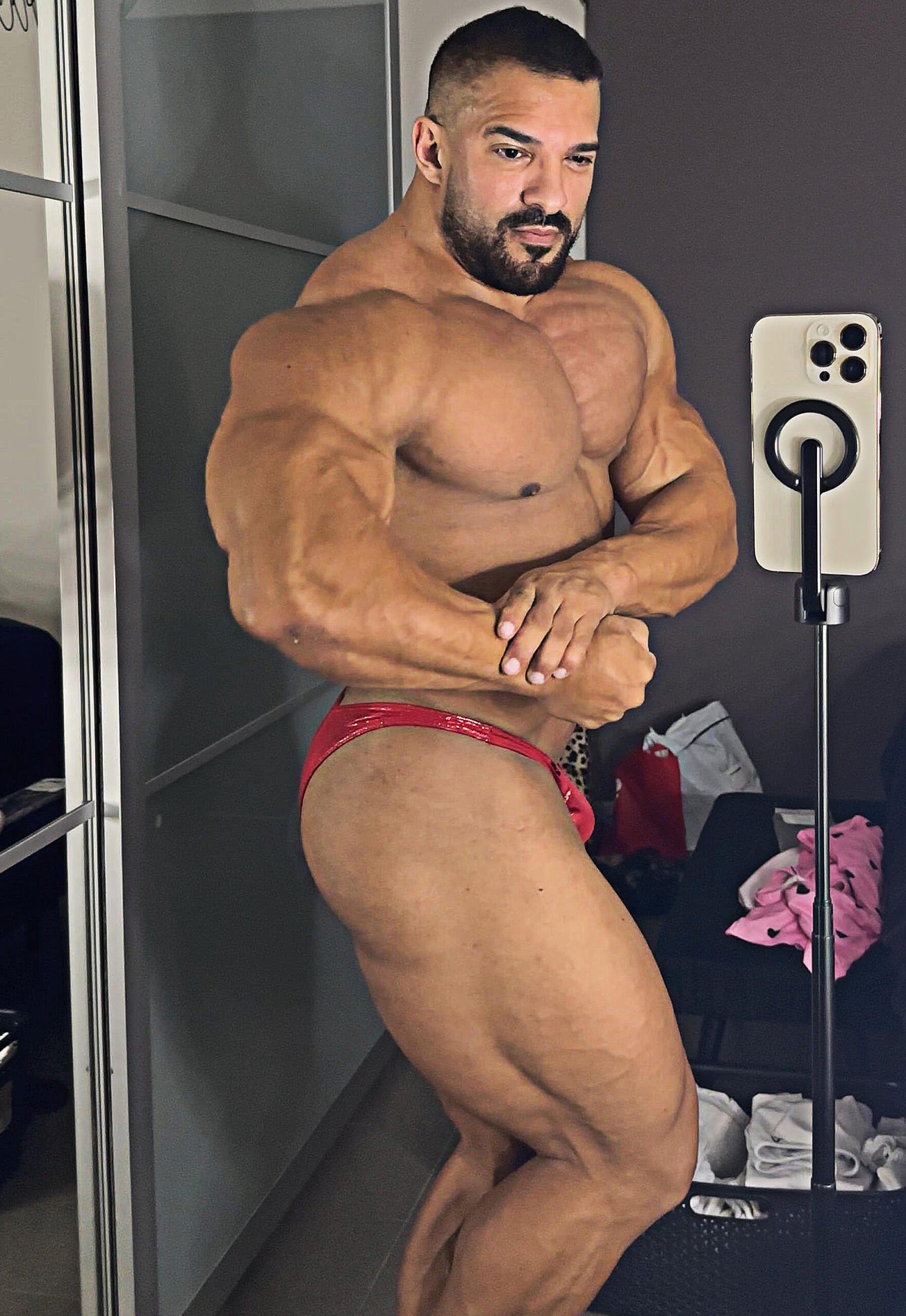 Lars Gorilla showcasing his muscular bodybuilding physique in a side-chest pose, highlighting his chest, shoulders, arms, and leg development.